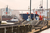 At Pedro Miguel Locks,near the Centennial Bridge,large shipping vessels and tugboats are stationed along the Panama Canal.,Panama