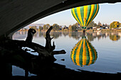 Von einer Brücke aus gesehen schwebt ein Heißluftballon der Prosser Balloon Rally über dem Yakima River, während ein Fotograf zuschaut,Yakima River,Prosser,Washington
