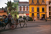 In der Abenddämmerung fährt eine Pferdekutsche mit Passagieren durch die Straßen von Havanna,Havanna,Kuba