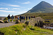 Hikers cross a bridge leading to a trail through the Cuillin Mountains near Sligachan,Isle of Skye,Scotland