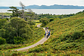 Touristen gehen einen gewundenen Pfad auf der Isle of Eigg, Schottland, Isle of Eigg, Schottland, entlang