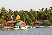 Inland river with fishing boat and Hindu temple in palm grove Goa,India,Panjim,Goa,India