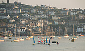 Kleine bunte Segelboote segeln im Hafen des Fischerdorfs Polruan in Cornwall, England.