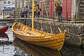 A replica of a small viking boat in a harbor.