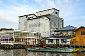 Gebäude und traditionelle Boote entlang des Ufers des Kumai River.