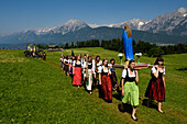 The procession to celebrate the Herz-Jesu Festival enters a large meadow overlooked by the Karwendel mountain range.,Austria.