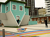 Asiatische junge Frau posiert für ein Foto vor dem Upside Down House, Brighton, East Sussex, England