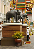 A soldier of the King's Guard and elephant statues in front of the Throne Hall.,Chakri Maha Prasad,The Grand Palace,Bangkok,Thailand.