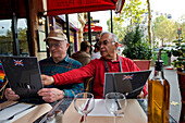 Zwei Männer sehen sich die Speisekarten in einem Restaurant in Paris, Frankreich, Paris, Frankreich an