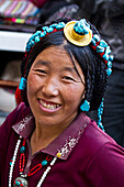 Lächelnde Frau mit Kopfschmuck auf dem Borkhar-Markt, Lhasa, Tibet