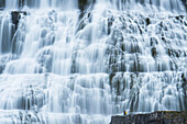 Touristen besuchen den Dynjandi-Wasserfall, auch Fjallfoss genannt, in den Westfjorden, Island, Island