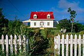 Cozy cottage along the coast with a red roof and white picket fence,Gaspe,Quebec,Canada