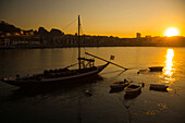 Boot mit Weinfässern im Hafen von Porto bei Sonnenuntergang, Porto, Portugal