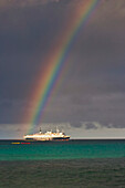 Regenbogen leuchtet über einem Passagier-Expeditionsschiff auf den Galapagos-Inseln, Insel Espanola, Galapagos-Inseln, Ecuador