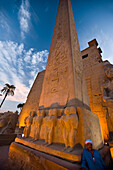 Man stands next to an illuminated obelisk at Luxor Temple,Luxor,Egypt