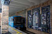 Zug fährt auf den Gleisen vorbei an Kunstwerken an den dekorierten Wänden der Toshkent Station für die Tashkent Metro in Usbekistan, Tashkent, Usbekistan