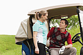 Pärchen mit Golfwagen auf Golfplatz