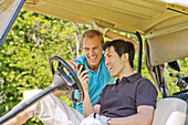 Mann im Golfwagen liest Textnachricht