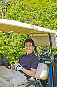 Mann im Golfwagen hält Mobiltelefon