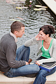 Universitätsstudenten, die zusammen an einem Teich sitzen