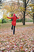 Frau hüpft durch Herbstlaub