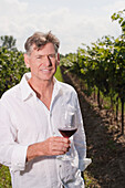Porträt eines Mannes im Weinberg, der ein Glas Wein hält