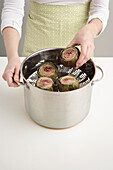 Woman Putting Artichokes in Steamer