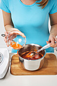 Woman Making Red Pepper Jelly,Skimming Top Layer Into Bowl