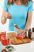 Woman Pouring Red Pepper Jelly Into Jars