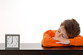 Boy Sleeping Next to Alarm Clock