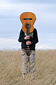 Junge hält Gitarre im Feld