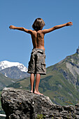 Rückenansicht eines Jungen, der auf einem Felsen steht, Alpen, Frankreich