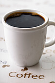 Nahaufnahme einer Tasse schwarzen Kaffees mit Kaffeetext, Studioaufnahme
