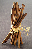 Close-up of Cinnamon Sticks tied with Raffia on Grey Background,Studio Shot