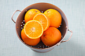 Draufsicht auf Orangen im Sieb auf blauem Hintergrund, Studioaufnahme
