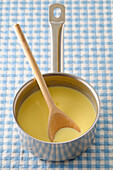 Overhead View of Vanilla Sauce and Wooden Spoon in Cooking Pot on Blue Gingham Background,Studio Shot