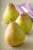 Close-up of Three Pears with Knife on Beige Background,Studio Shot