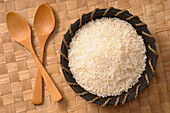 Draufsicht auf eine Schüssel mit weißem Reis mit Holzlöffeln