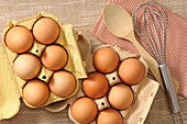Draufsicht auf Eier mit Holzlöffel, Schneebesen und Serviette