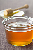 Nahaufnahme von Honig mit Honiglöffel im Hintergrund