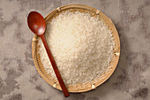 Overhead View of Uncooked Rice in Bowl with Wooden Spoon