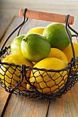 Zitronen und Limetten im Drahtkorb, Studioaufnahme