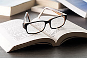 Nahaufnahme einer Brille auf einem aufgeschlagenen Buch, Studioaufnahme