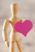 Wooden artist's mannequin holding heart