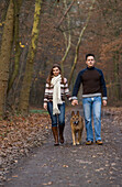 Paar geht mit seinem Hund im Wald spazieren