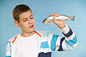 Junge hält rohen Fisch
