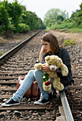 Teenager-Mädchen sitzt auf Bahngleisen
