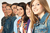 Nahaufnahme von sechs jungen Männern und Frauen in einer Reihe, lächelnd und in die Kamera blickend, Studioaufnahme vor weißem Hintergrund