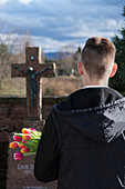 Teenager Standing in front of Grave Stones in Cemetery