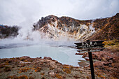 Gefahrenschild vor vulkanischem Feld und dampfendem Teich in Noboribetsu, Höllental, Hokkaido, Japan, Asien